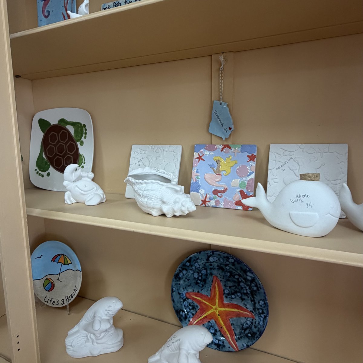 Unpainted pottery pieces beside finished painted plates on the shelves at Midnight Star Pottery in Richmond Hill
