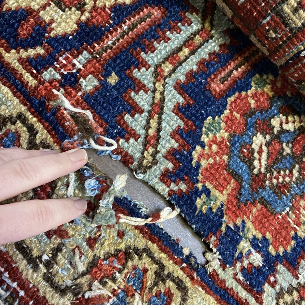Hands restoring a hand knotted rug at Savannah Galleries in Savannah